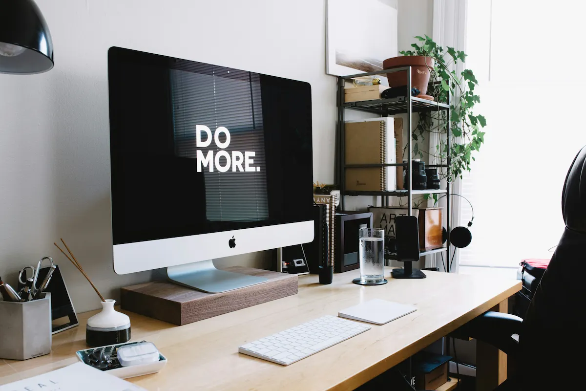Modern workspace with an iMac displaying 'DO MORE'